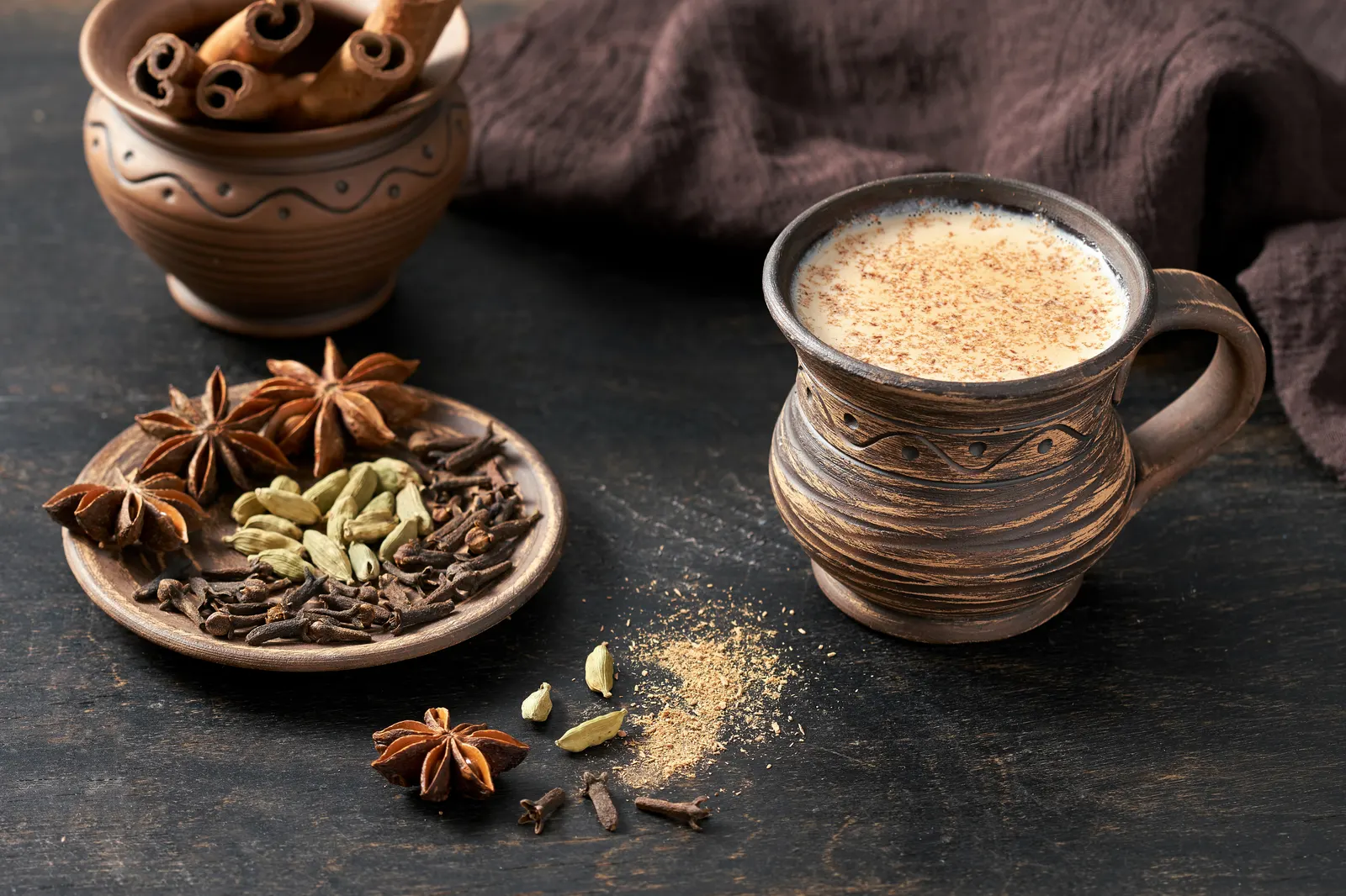 Spiced chai in a mug with cardamom, star anise, clove, and cinnamon